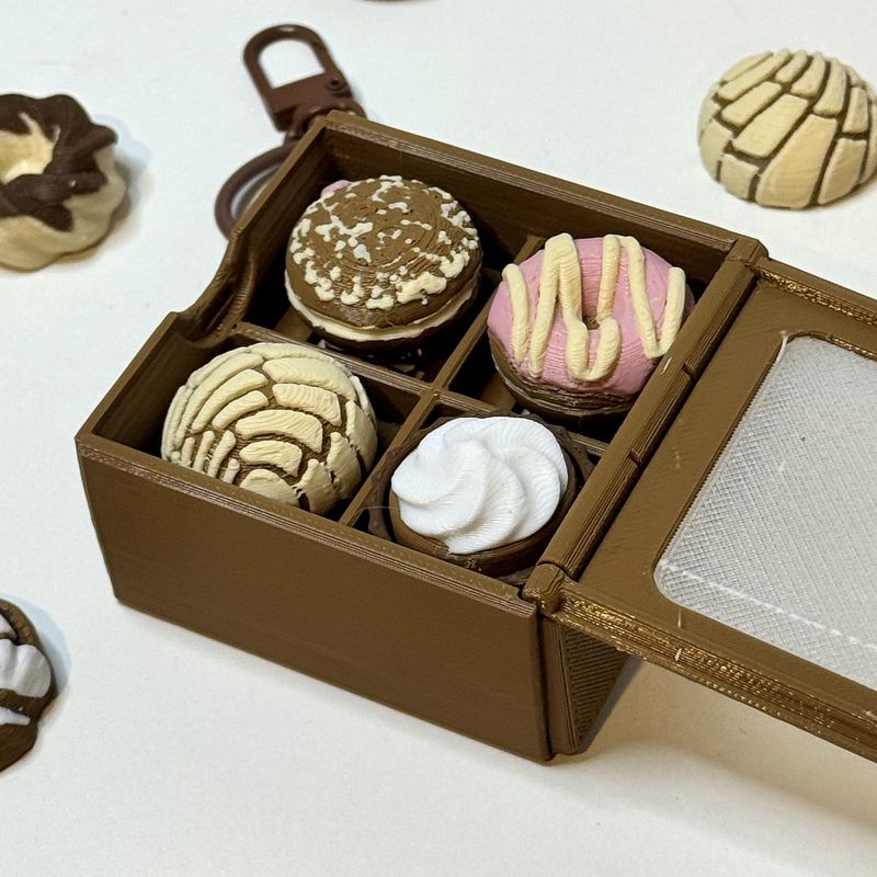 Open brown mini cake box holding four pastries